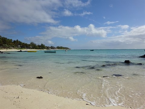 Boat on tropical beach, pale sand and turquoise water, sunlight