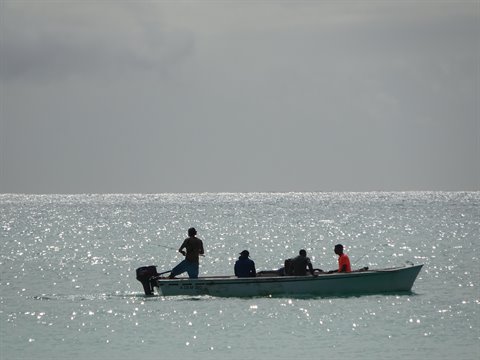 Motorboat with four people on sparkling sea under grey sky