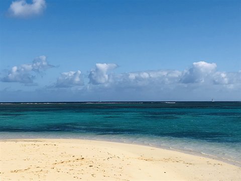 Pale sand and turquoise sea under blue sky with white clouds