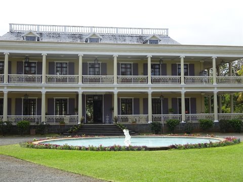 Old colonial mansion with double veranda, fountain in garden, diffuse light