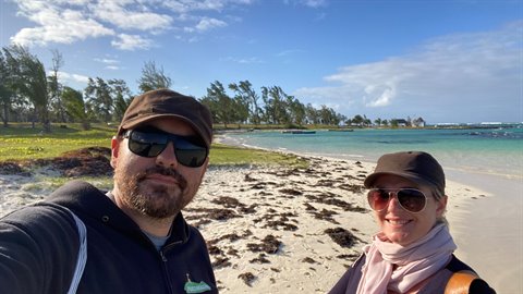 Couple in sunglasses and caps takes a selfie on a sandy beach