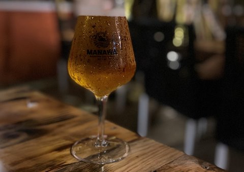Condensation-covered glass of beer on wooden table in a pub