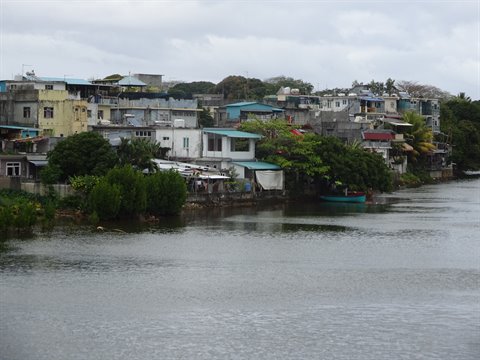 Colorful houses along riverbank, small blue boat, soft cloudy daylight
