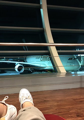 White sneakers in foreground, airliner parked at night beyond the airport window