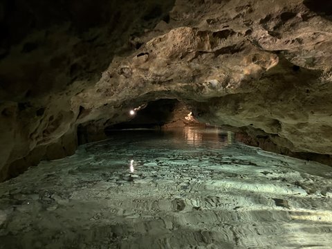 Underground cave with turquoise lake, limestone rock lit by artificial lights