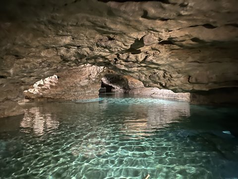 Clear turquoise water inside a rocky cave, natural light filters through the opening