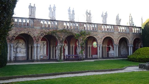 Brick arcaded gallery with statues on top, natural daylight