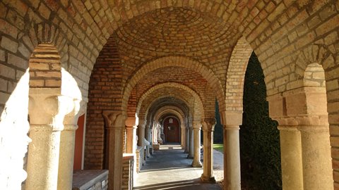Brick-vaulted colonnade with stone columns, sunlight on the arch