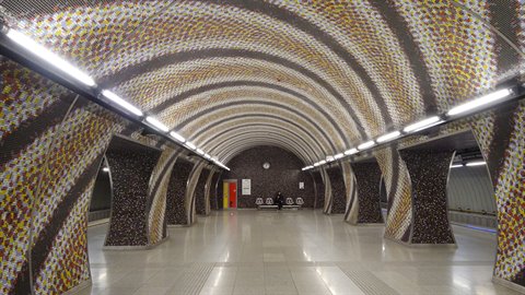 Metro station interior with multicolored mosaic vaulted ceiling, fluorescent lights, empty floor