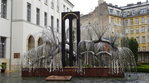 Metal willow memorial sculpture in a synagogue courtyard, soft light