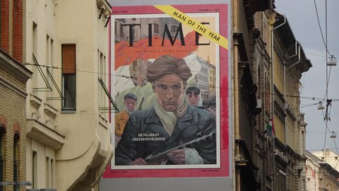 Printed copy of a Time magazine cover posted on a wall between historic buildings