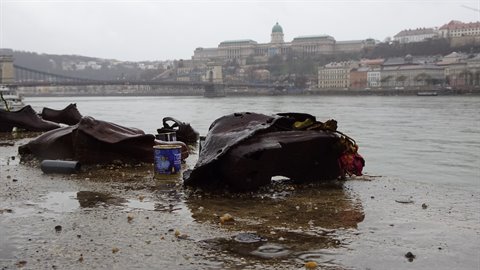Rusted iron and cans on muddy riverbank, historic palace and bridge over grey water
