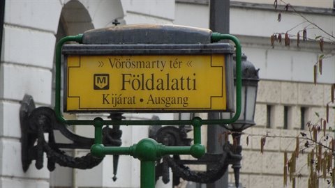 Yellow metro sign on a green pole in front of a building