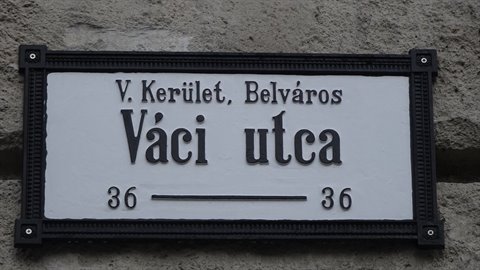 Black and white enamel street sign mounted on grey stone wall