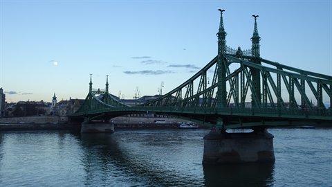 Green iron bridge over the river under twilight sky with moon