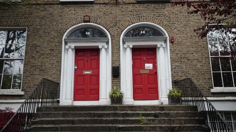 Twin red doors on brick facade, soft daylight, stone steps leading up