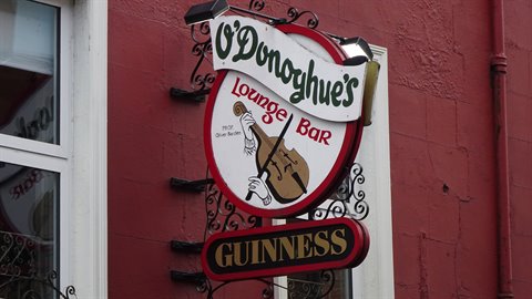 Circular pub sign with fiddle and Guinness lettering on a red wall
