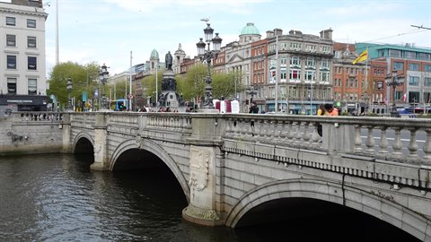 Stone bridge with arches over a city river, daylight, pedestrians walking