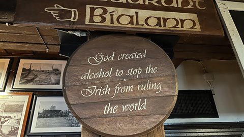 Round wooden sign with painted lettering hanging on a pub wall