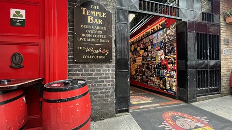 Temple Bar entrance with golden sign, red barrels and dark brickwork