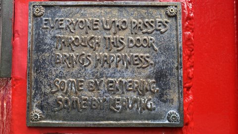 Metal plaque with engraved quote on red door, natural light, travel journal