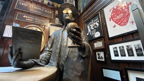 Bronze statue of James Joyce with book and goblet inside Temple Bar pub in Dublin