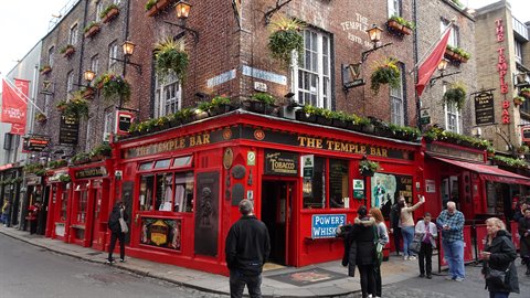 Tourists outside the red Temple Bar pub, brick facade with hanging flowers, soft daylight