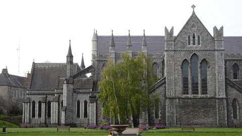 Gothic stone cathedral with spires, green lawn, white sky, diffused light