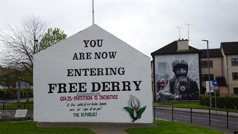 White painted wall reading Free Derry with soldier mural, urban street, overcast light