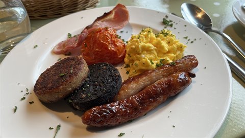 English breakfast plate with scrambled eggs, sausages and bacon, natural light
