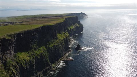 Green cliffs plunging into the ocean, low sunlight, travel journal page