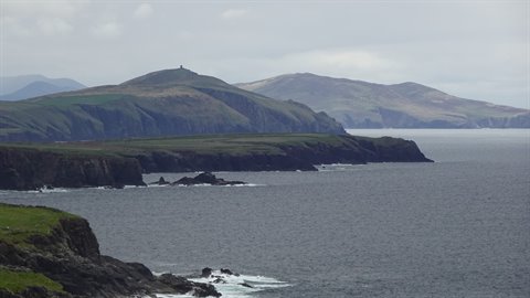 Dark green cliffs stretch into the grey sea under an overcast sky