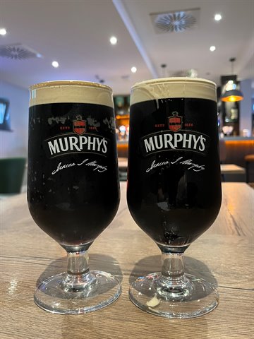 Two Murphy's stout glasses on wooden table in a warmly lit pub