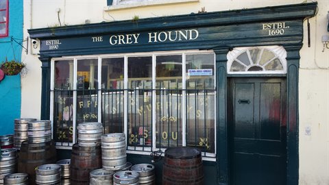 Pub facade with stacked beer kegs, historic sign, daylight