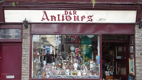 Antique shop window filled with assorted objects, red and white sign, daylight