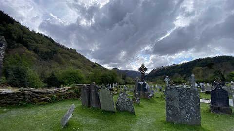 Ancient graveyard with Celtic crosses and stone tombstones under cloudy sky