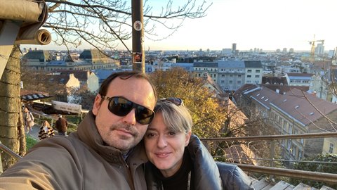 couple selfie on a hillside above red rooftops in winter sun