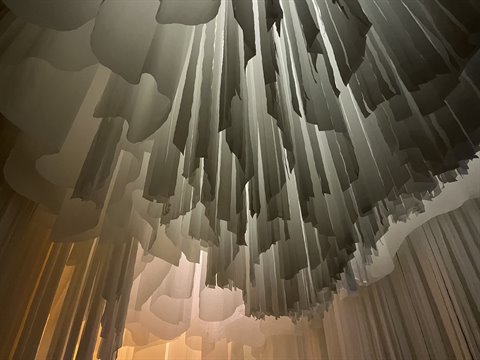Suspended paper installation, white layered sheets lit by warm light