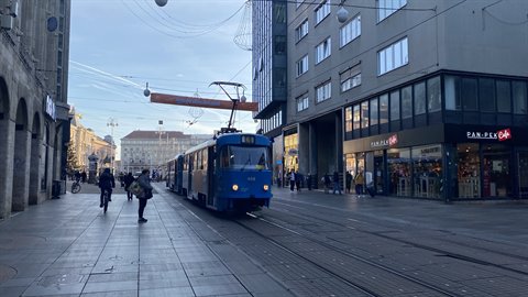 Blue tram crosses Ban Jelačić Square among pedestrians and shops