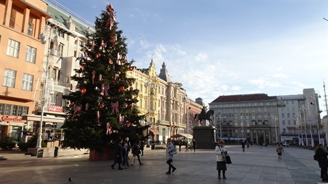 Decorated Christmas tree on Ban Jelačić Square in Zagreb, pedestrians walk among historic buildings