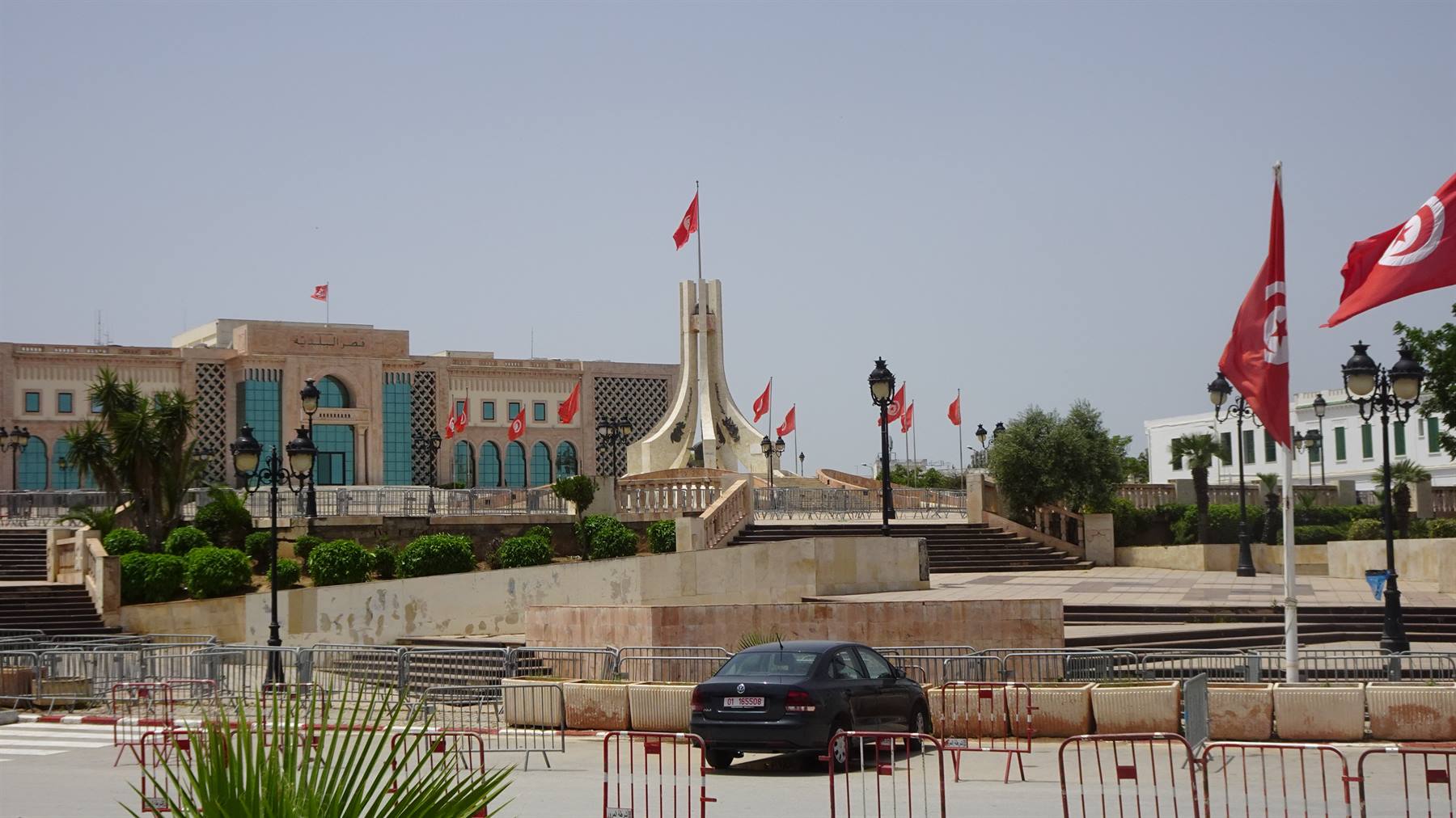 Piazza della Kasbah a Tunisi: monumento bianco, bandiere tunisine, auto ferma