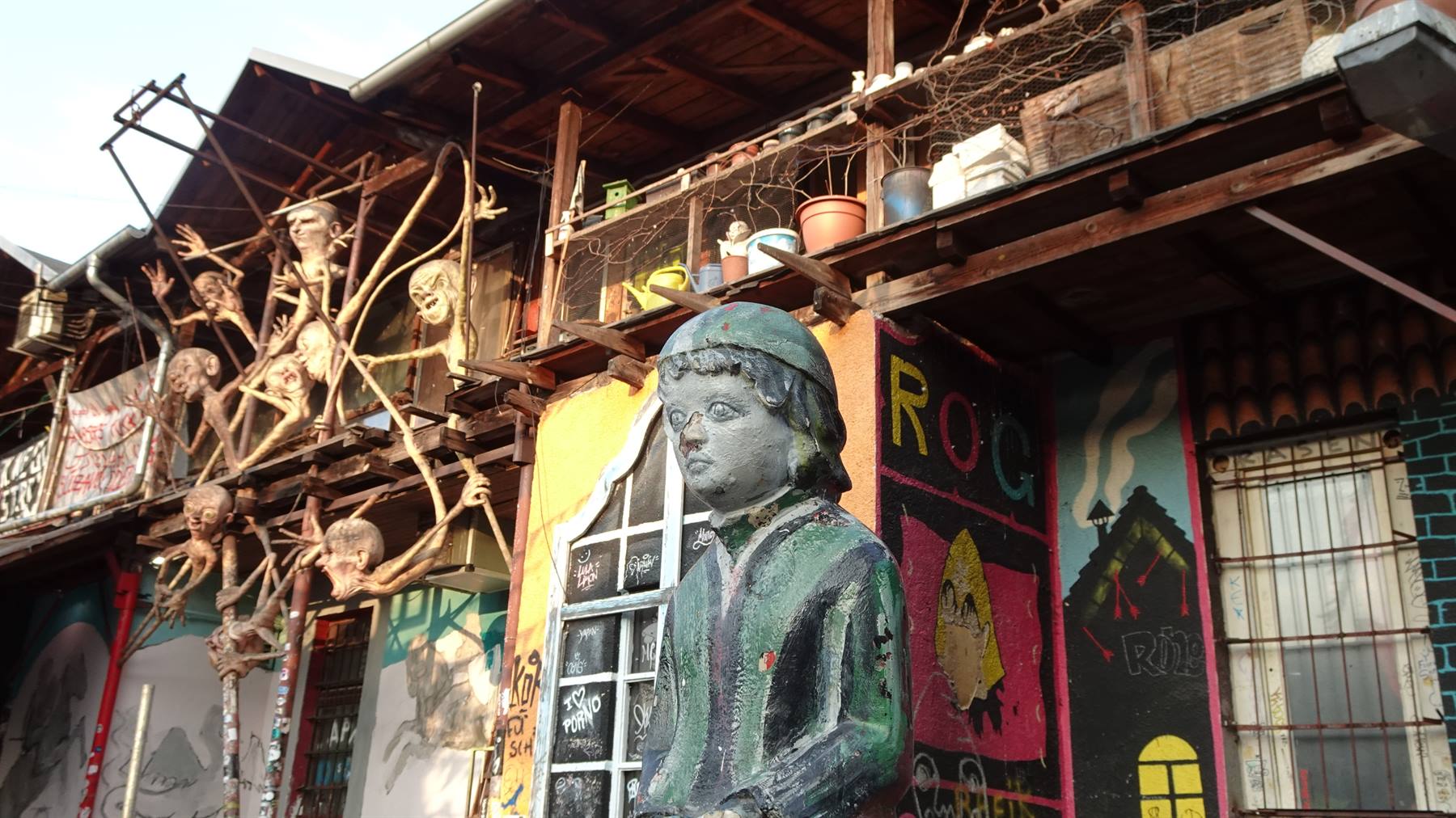 Statua di bambino davanti alle sculture e graffiti di Metelkova, Ljubljana