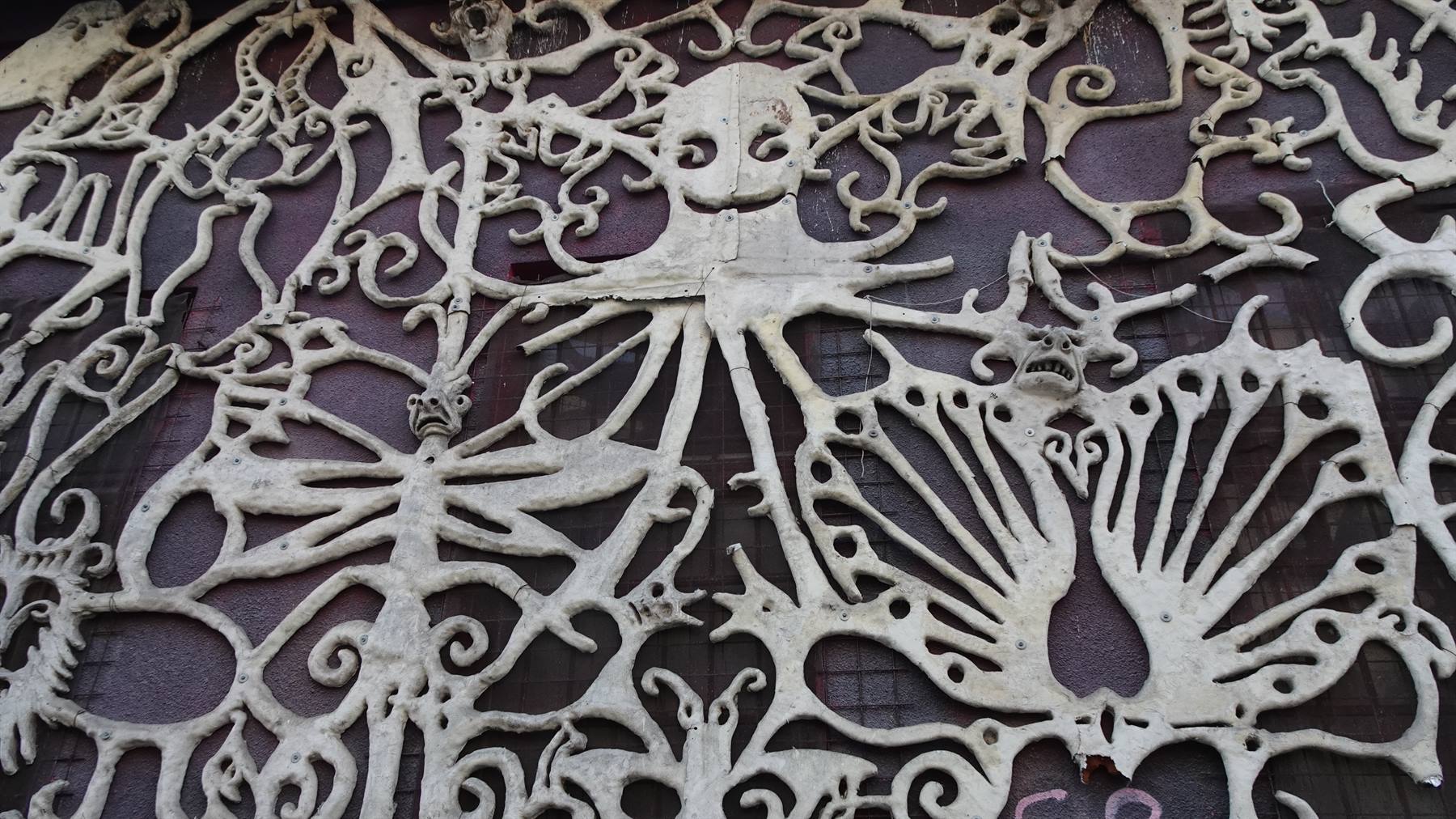 Decorazione scultorea in ossa bianche con figure fantastiche su muro scuro