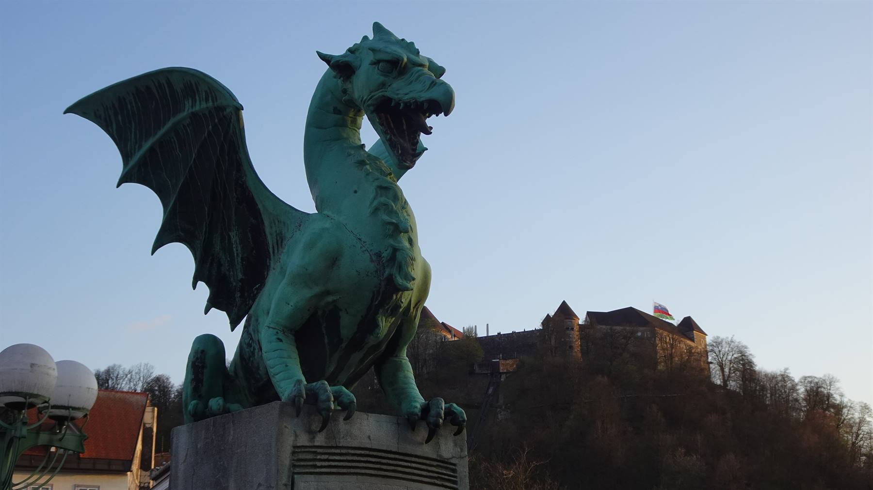 Drago di bronzo verde sul Ponte dei Draghi, dietro il castello di Lubiana