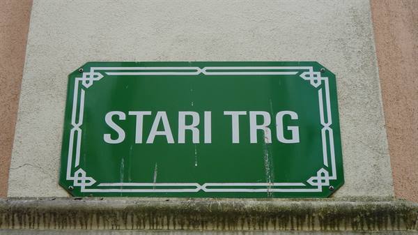 Green street sign with white lettering Stari Trg on plastered wall