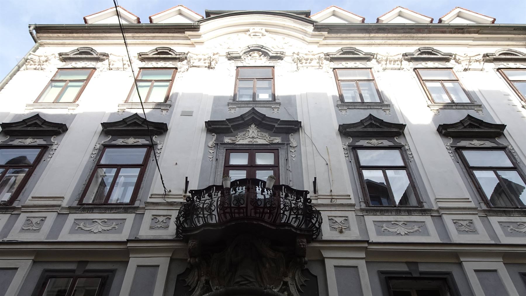 Facciata barocca bianca con balcone in ferro battuto, luci e ombre
