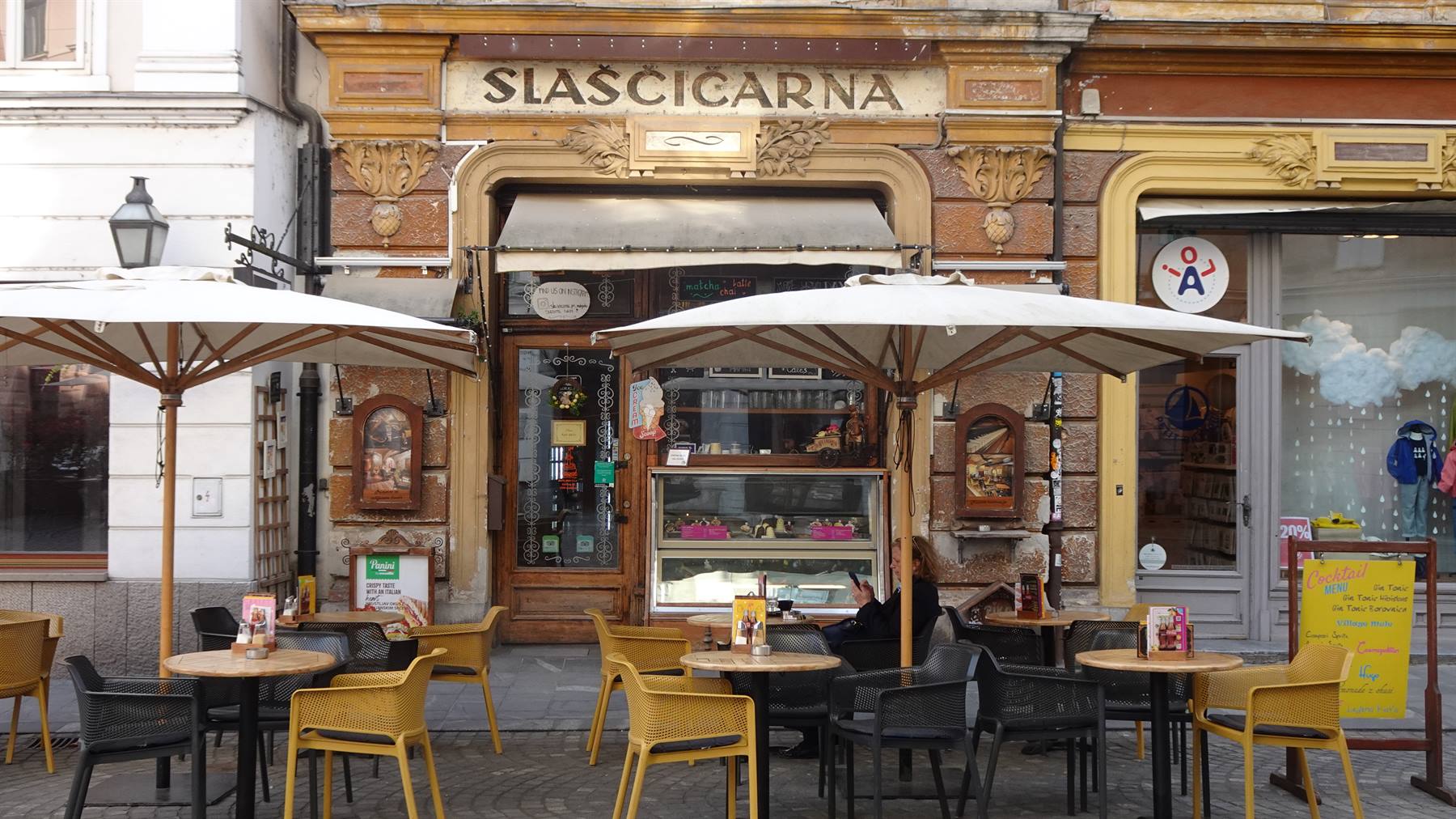 Tavolini con ombrelloni davanti alla Slascicarna, antica pasticceria su pregna facciata dorata