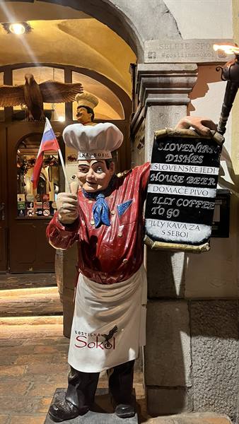 Chef statue holding Slovenian flag outside Gostilna Sokol tavern in Ljubljana