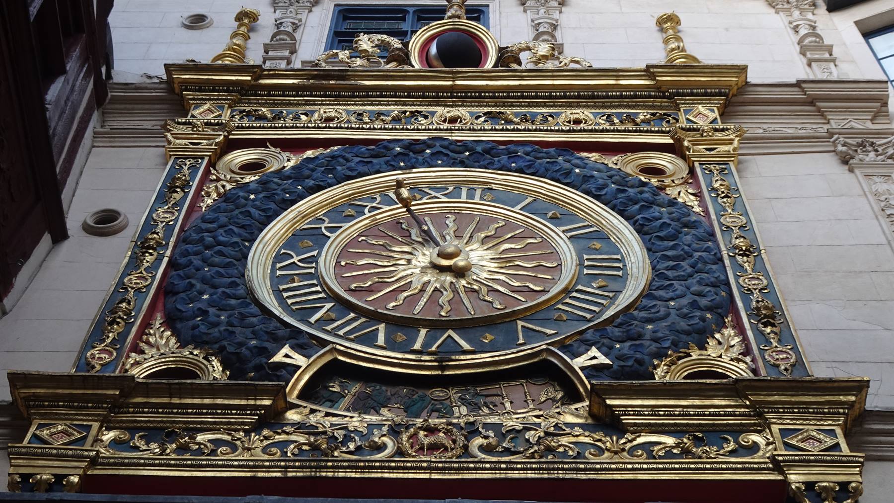 Orologio astronomico dorato con sole raggiato su facciata di Rouen
