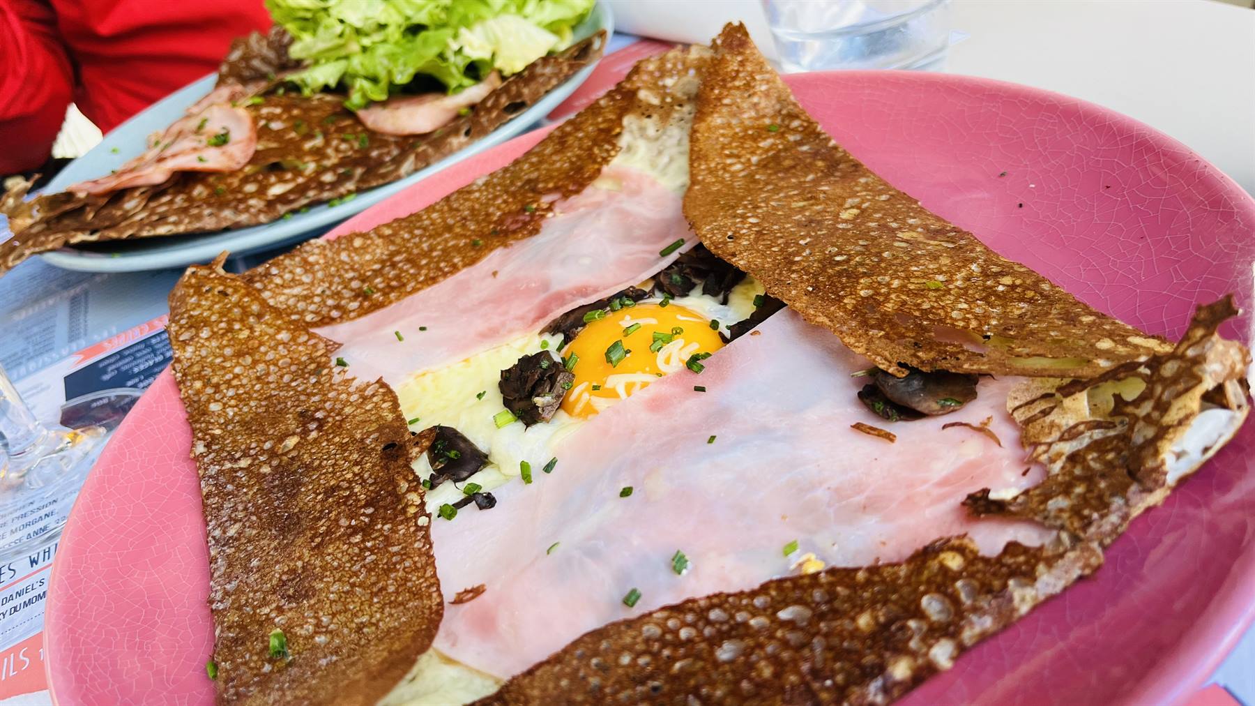 Galette di grano saraceno con prosciutto, formaggio e uovo su piatto rosa